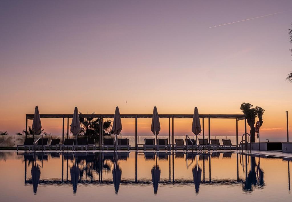 una piscina de agua con sombrillas y sillas en Estival Torrequebrada, en Benalmádena