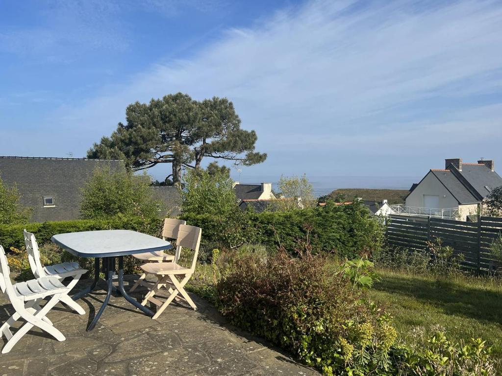 une table et des chaises dans une cour avec un arbre dans l'établissement 356 - Maison vue mer pour 8 voyageurs, à Fréhel., à Fréhel