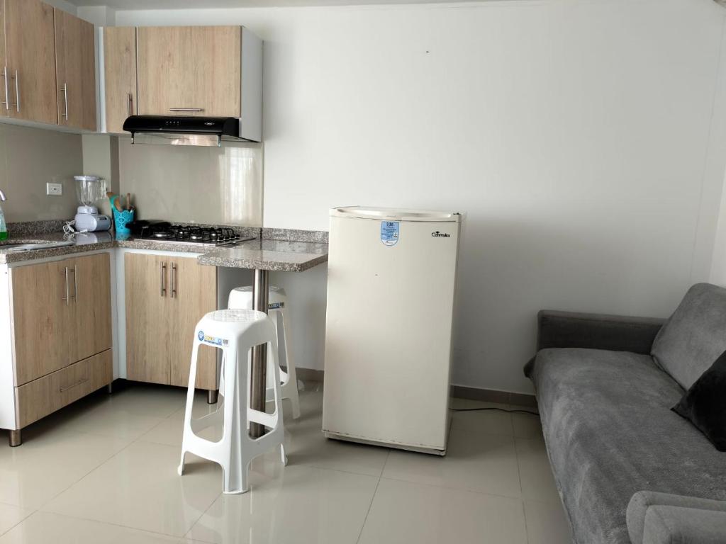 uma cozinha com um frigorífico e um banco num quarto em Aparta-hotel medilaser-Uniboyaca em Tunja