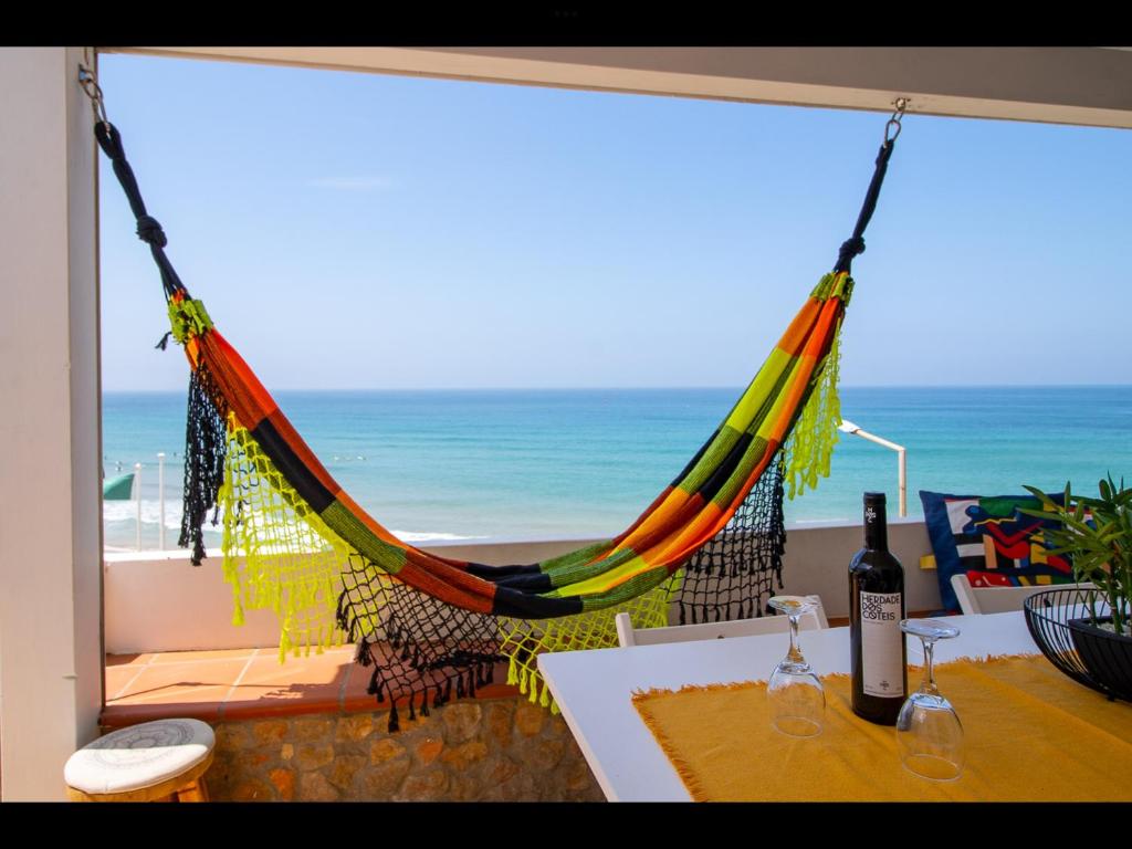 a hammock in a room with a view of the beach at 2 bedrooms house at Aljezur 100 m away from the beach with sea view furnished terrace and wifi in Aljezur