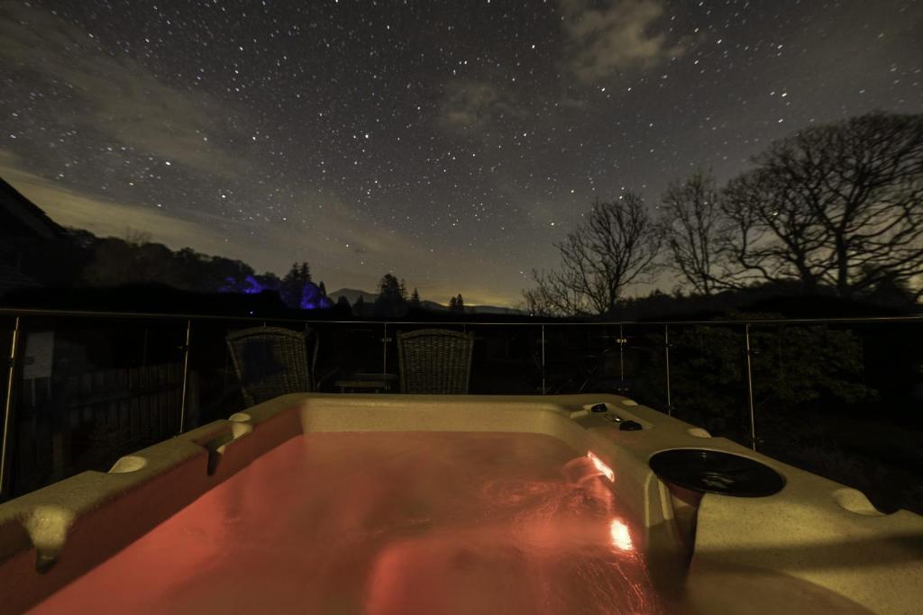 un bain à remous sur un balcon sous un ciel étoilé dans l'établissement Fox Corner, Ambleside, romantic retreat for two, dog friendly, hot tub, à Ambleside