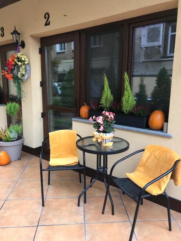 a patio with two chairs and a table with flowers on it at Spadzista 2 in Kłodzko