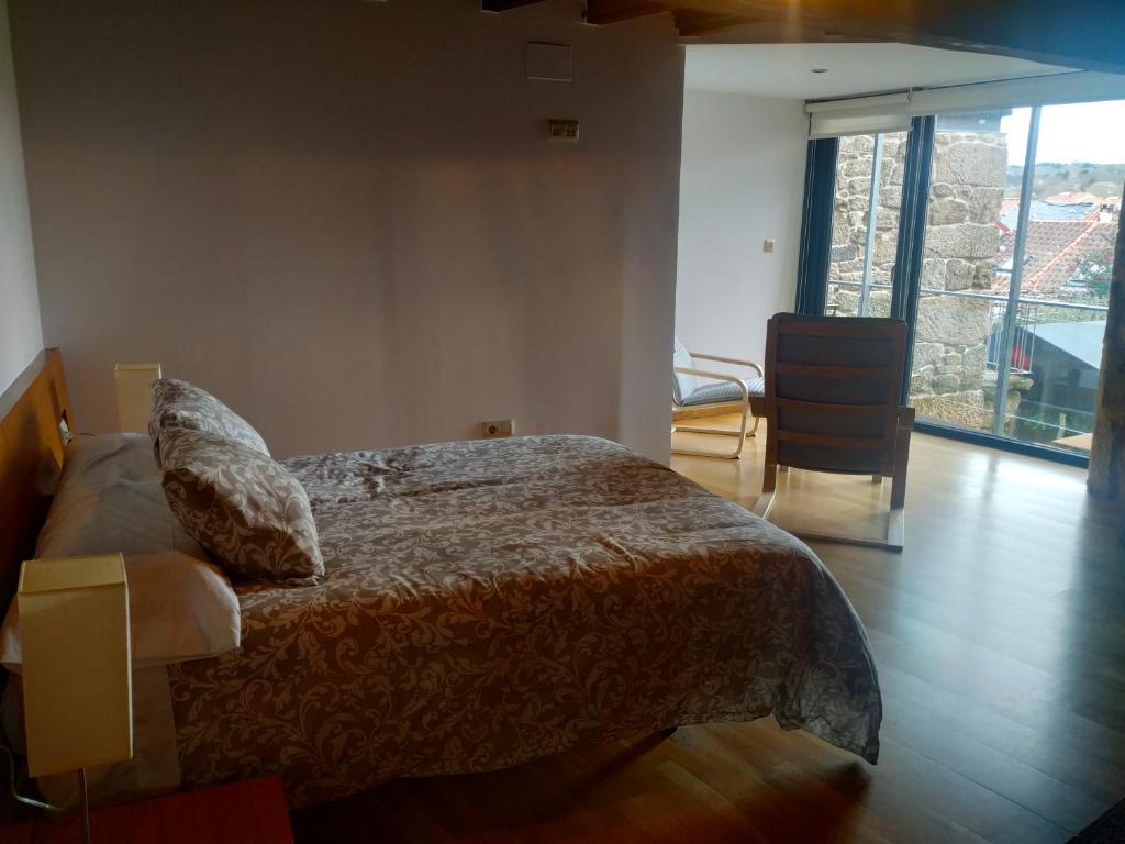 een slaapkamer met een bed en een groot raam bij Pensión rural Pallabarro in Allariz