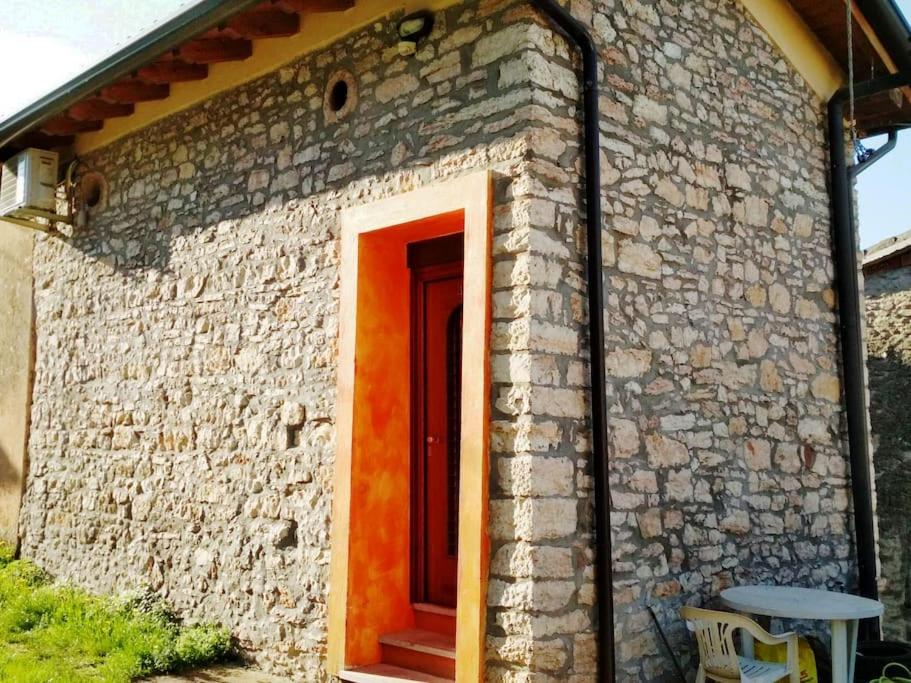 a brick building with a red door and a table at Fienile ristrutturato in Zago