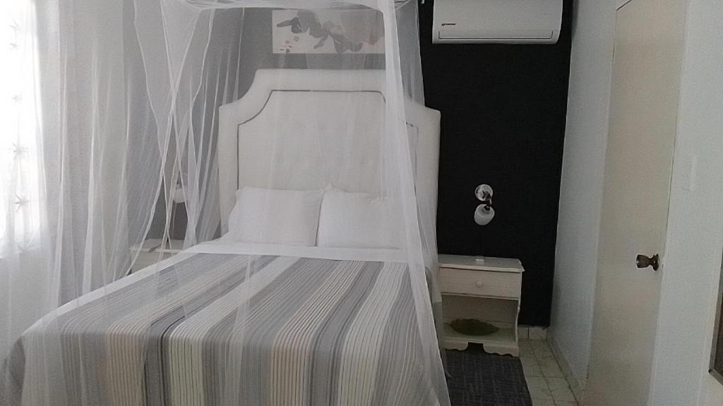 1 cama blanca con dosel en una habitación en Csompó Cozy One Bedroom Apartment Beach property, en Saint Mary