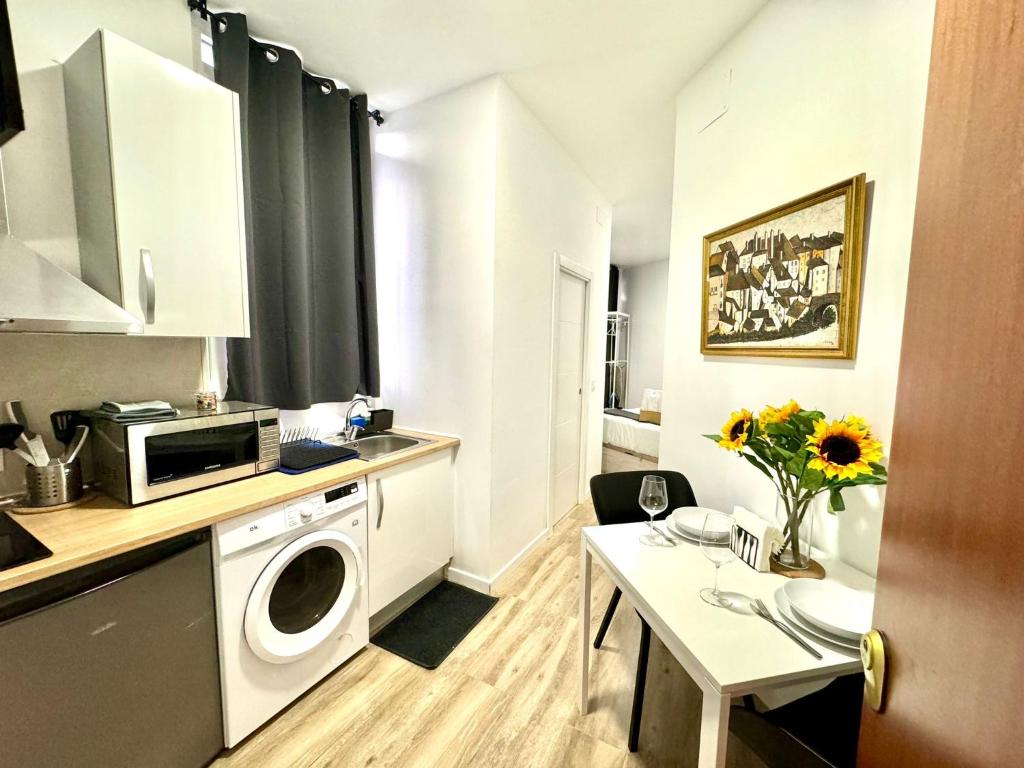 uma pequena cozinha com uma máquina de lavar roupa e uma mesa em Apartamentos Madrid Connection - Universidad by Oshun Apartments em Madri