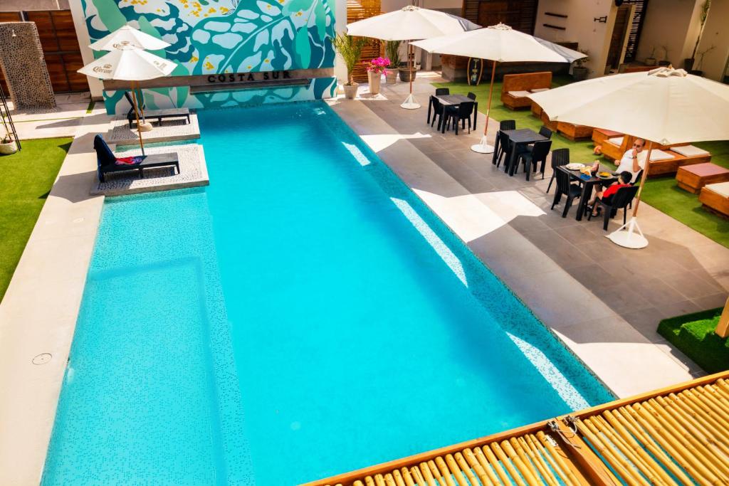 カマナにあるHotel Costa Surのテーブルとパラソル付きのスイミングプールのオーバーヘッドビュー