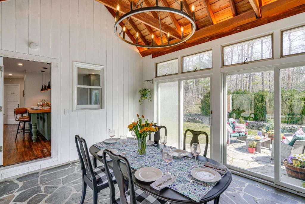 a dining room with a table with chairs and a chandelier at Saugerties Farmhouse with Patio and Countryside Views! in Saugerties