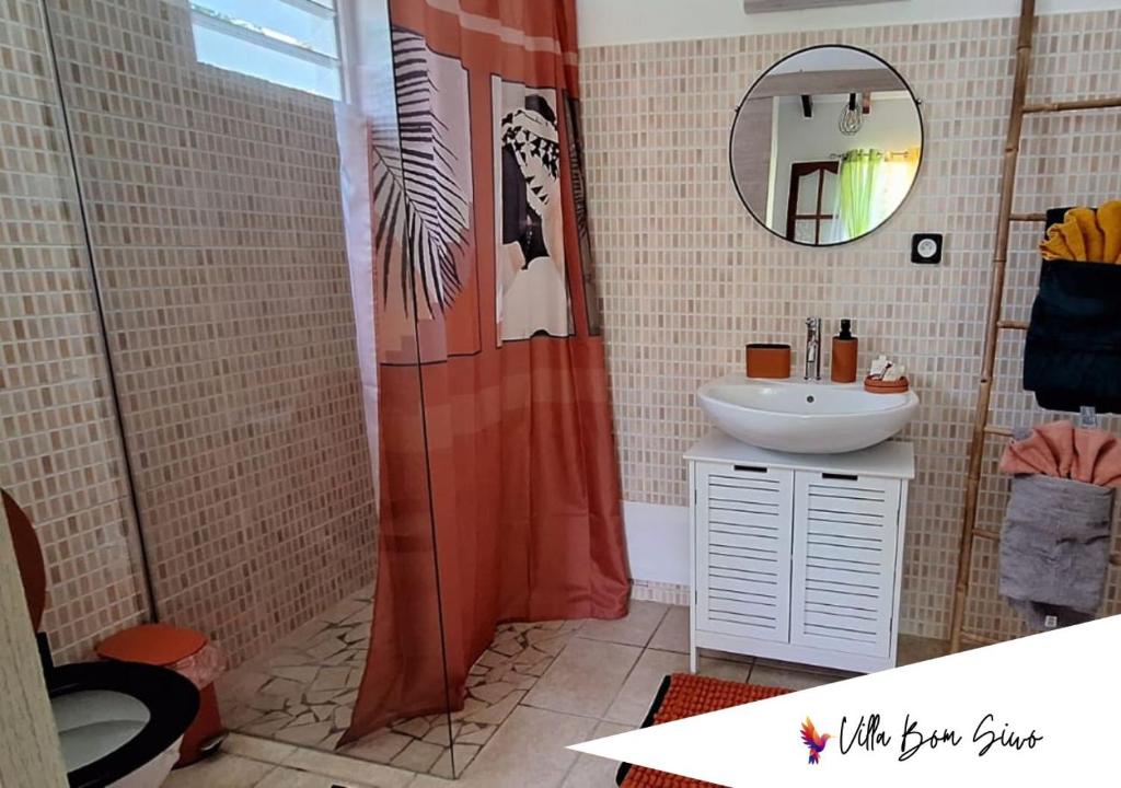 a bathroom with a shower curtain and a sink at Villa Bom Siwo: Anse Bertrand in Anse-Bertrand