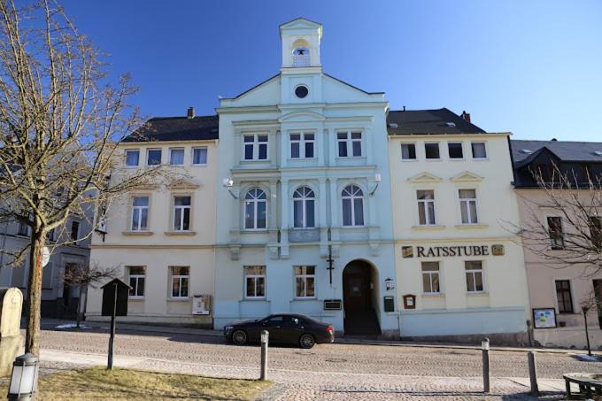 un bâtiment avec une voiture garée devant lui dans l'établissement Rathaushotel, à Eibenstock