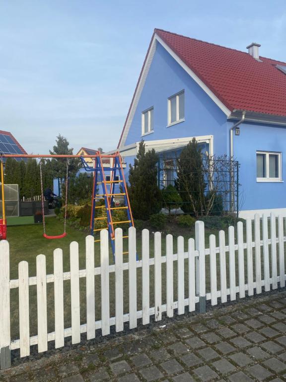 ein weißer Gartenzaun vor einem blauen Haus in der Unterkunft Ferienwohnung Patrick in Amberg