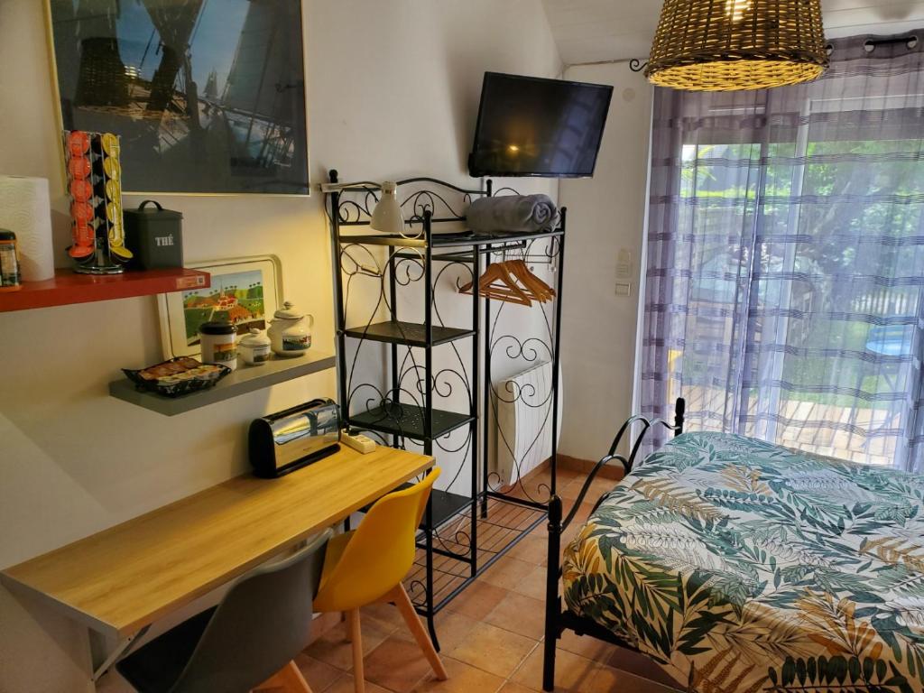 セネにあるStudio au calme, dans village tranquilleのデスク、ベッド、テーブルが備わる客室です。