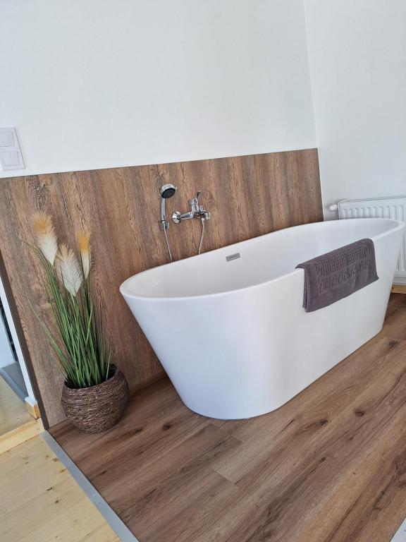 a white bath tub in a bathroom with a wooden floor at Várfal apartman II in Eger