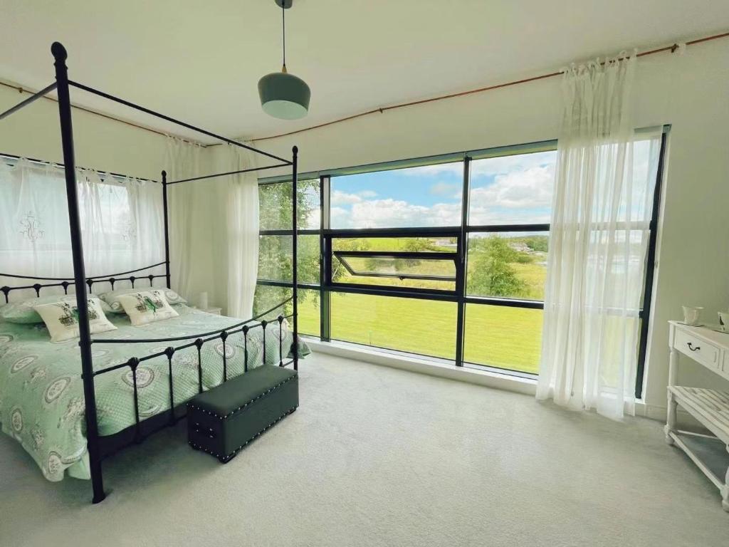ein Schlafzimmer mit einem Bett und einem großen Fenster in der Unterkunft 湖景度假屋Lakeview Vacation Home in Belturbet