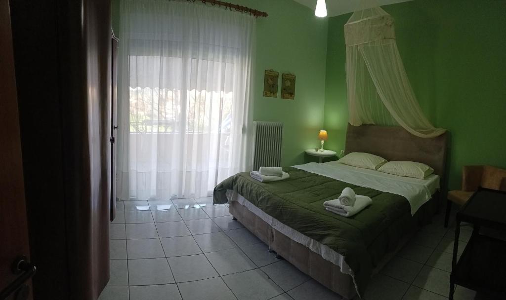 Un dormitorio con una cama con paredes verdes y una ventana en Daphne's apartment en Kavala