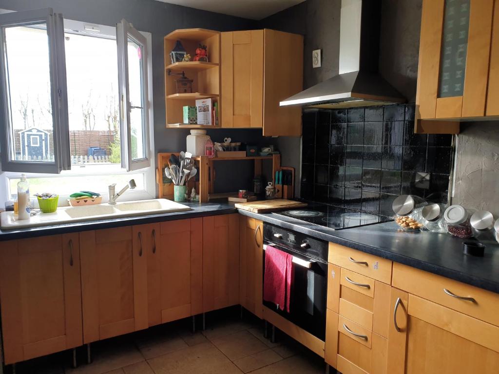 uma cozinha com armários de madeira e um forno com placa de fogão em Chez Thai et Isabelle em Oissery