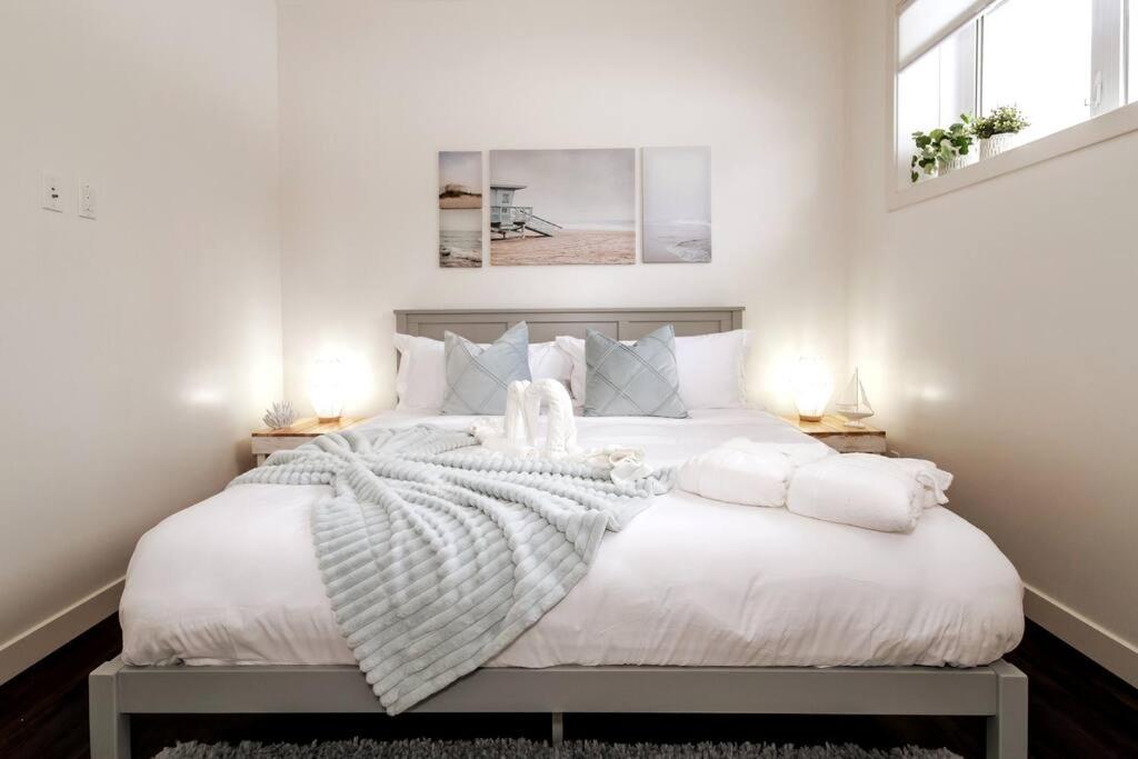 a white bedroom with a large bed with white sheets and pillows at Beach Vibes - KING Bed - Fireplace - Garage - WiFi in Edmonton
