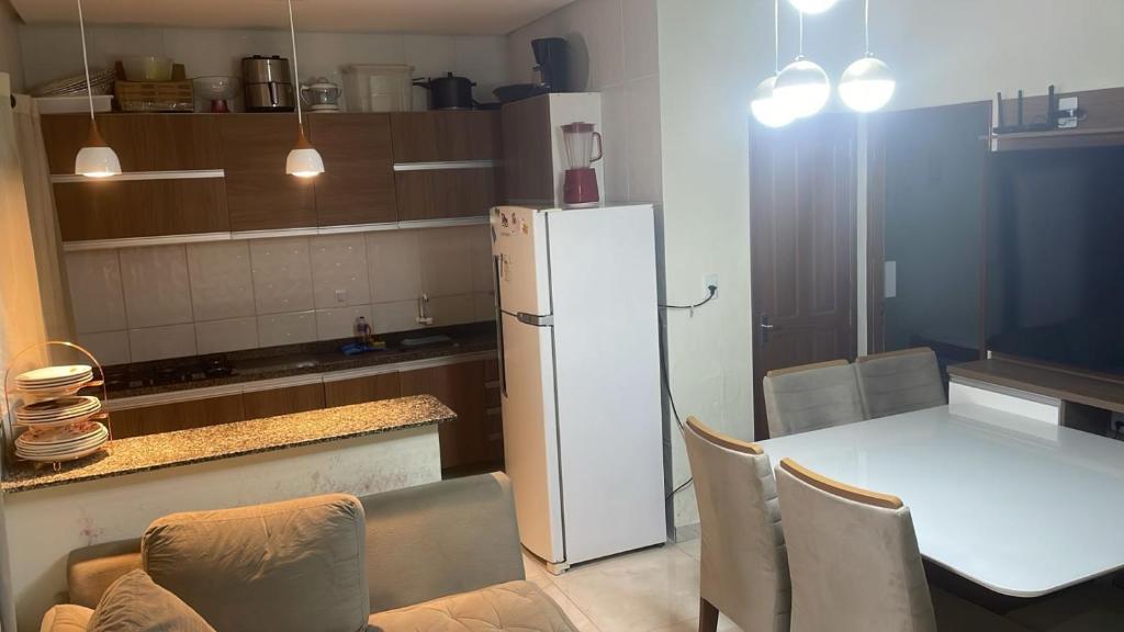 eine Küche mit einem Tisch und einem weißen Kühlschrank in der Unterkunft Casa 2 Quartos Manaus in Manaus