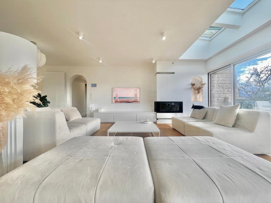 un salon avec des meubles blancs et une grande fenêtre dans l'établissement Villa contemporaine d'architecte, à Bonneville