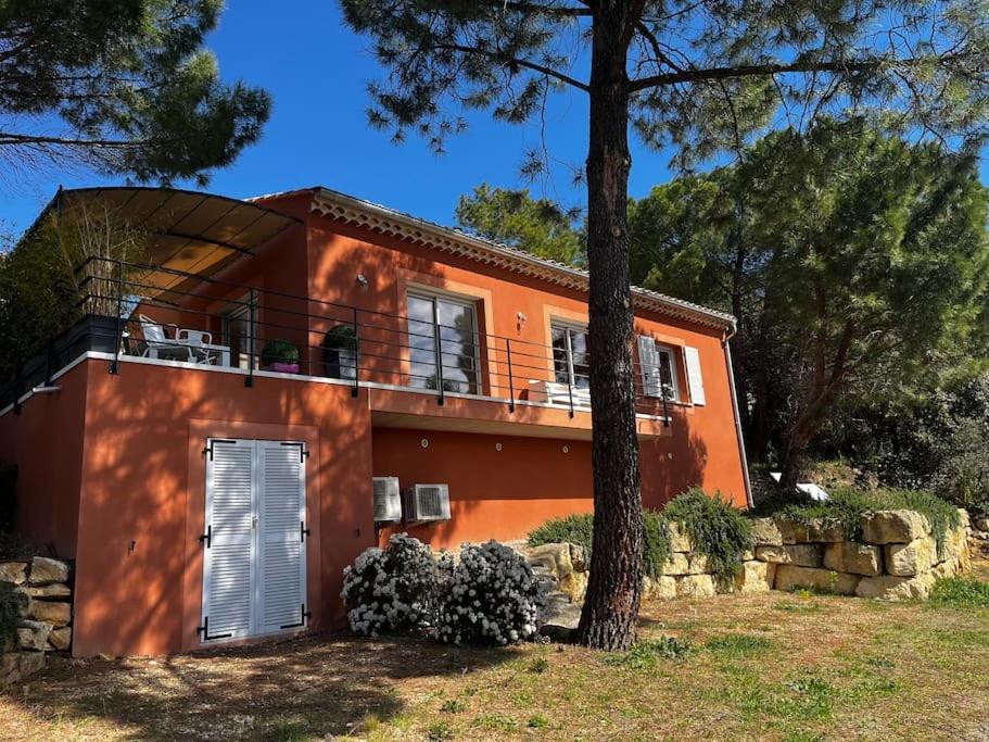 a orange house with a balcony and a tree at La villa Rosa in Bédoin