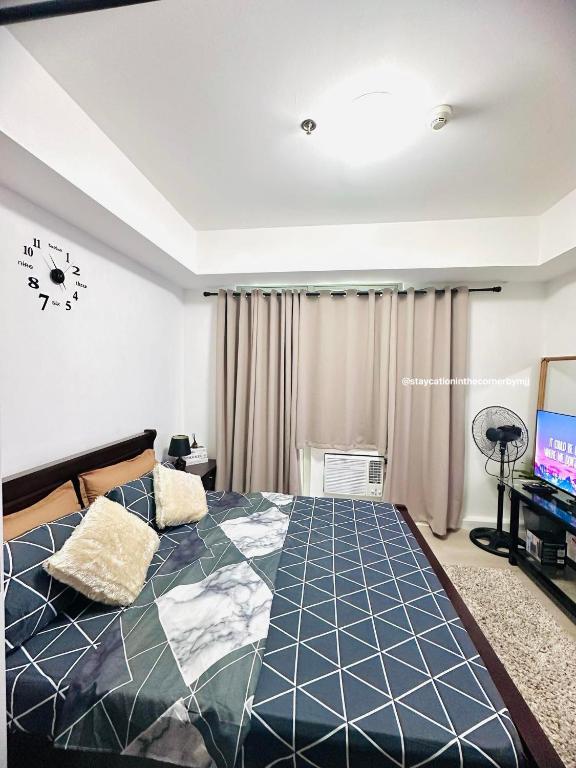 a bedroom with a large bed and a tv at Staycation in the Corner by MJJ in Manila