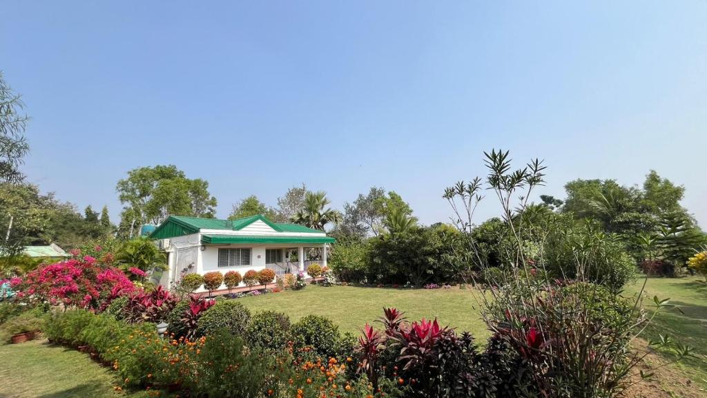 a small white house with a green roof in a garden at The Red Soil Country in Siuri