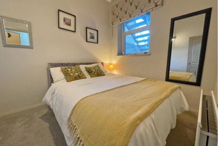 une chambre avec un grand lit et un miroir dans l'établissement Beside West Strand beach Portrush Ground Floor Apartment, à Portrush