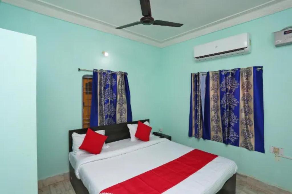 - une chambre avec des murs bleus et un lit avec des oreillers rouges dans l'établissement Hotel Madison Patia Inn Bhubaneswar, à Bhubaneswar
