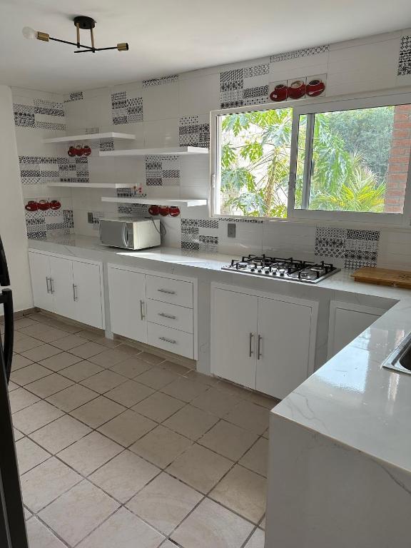 eine weiße Küche mit weißen Schränken und einem Fenster in der Unterkunft Habitación privada en casa compartida. in Tepic