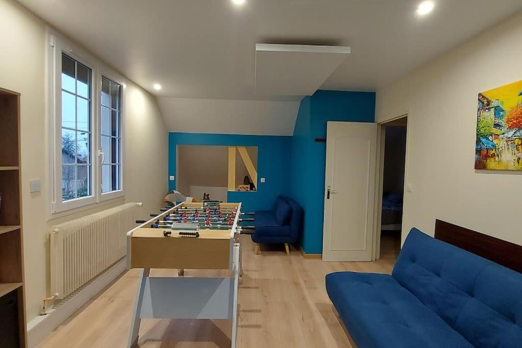 - un salon avec une grande table de jeux et des murs bleus dans l'établissement F3 avec salle de jeux, terrasse et grand jardin, à Villevaudé