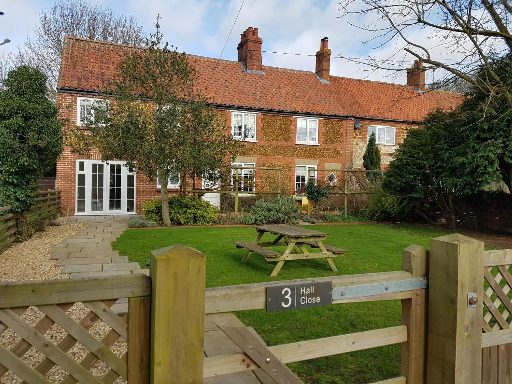 a house with a wooden fence and a picnic table at Gorgeous Cottage by the sea sleeps 10 5 bed 4 bath in Heacham
