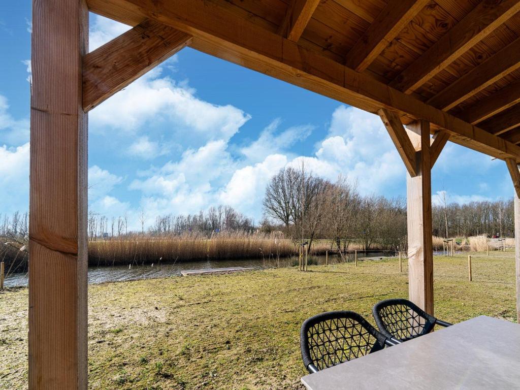 een veranda met een tafel en stoelen en uitzicht op een veld bij Nice holiday home with sauna near a lake in Simonshaven