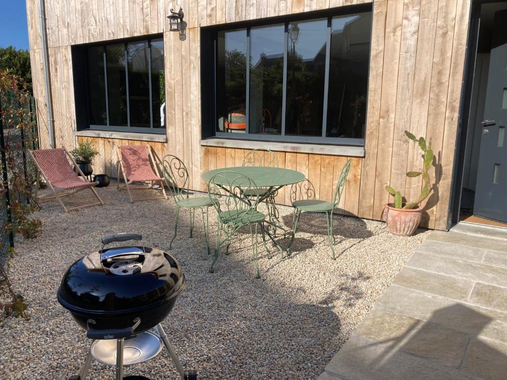 eine Terrasse mit einem Grill, einem Tisch und Stühlen in der Unterkunft Gîtes des Guettes in Saint-Suliac