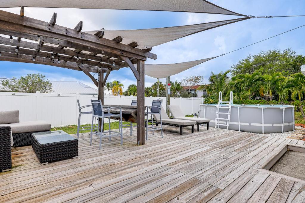 a deck with a table and chairs and an umbrella at Pet-Friendly Fort Pierce Home with Deck and Pool! in Fort Pierce