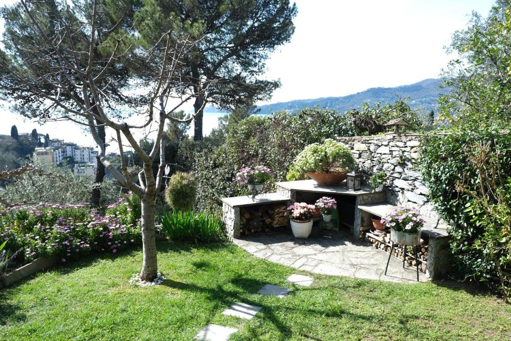a garden with a table and bench and flowers at L'Alcova tra gli Ulivi by PortofinoVacanze in Zoagli