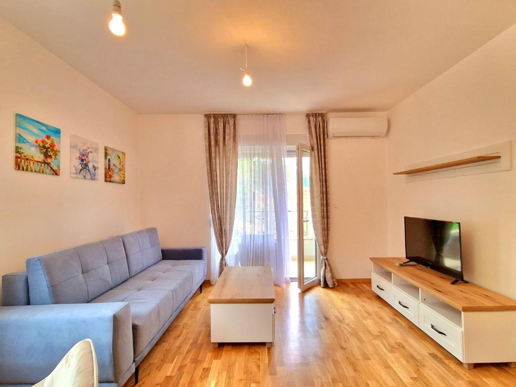 uma sala de estar com um sofá azul e uma televisão em VOLNA 59 APARTMENT em Budva