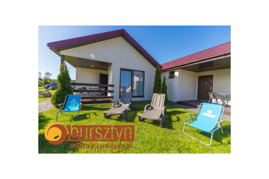 una casa con sillas y una mesa en el patio en Bursztyn II Domki Apartamenty Pokoje w Sarbinowie blisko morza en Sarbinowo