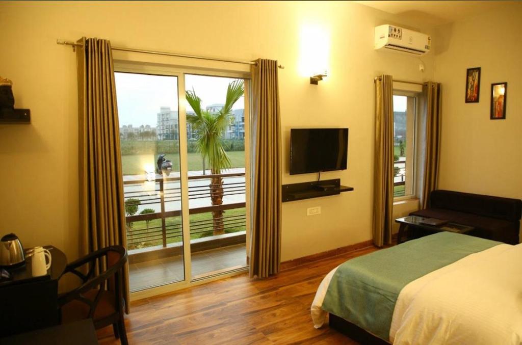 een slaapkamer met een bed en een groot raam met uitzicht bij Krishna Mahal Harmony in Vrindāvan