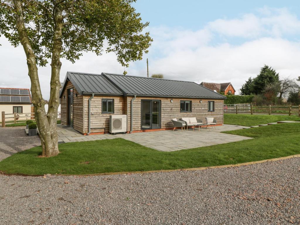 eine Blockhütte mit einer Terrasse und einem Baum in der Unterkunft Medlands in Newent