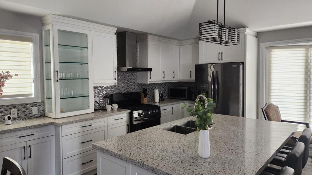 cocina con armarios blancos y encimera de granito en Amazing property to Enjoy. en Stouffville