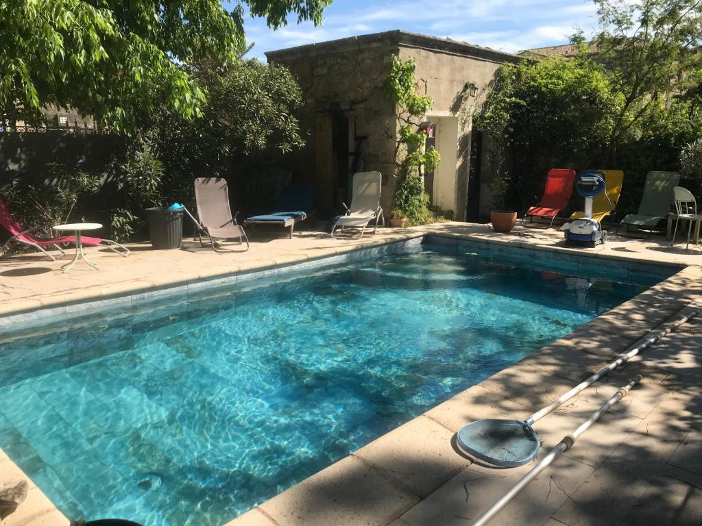 une piscine avec des chaises dans une cour dans l'établissement Maison 21, agréable maison de ville avec piscine, à Sommières