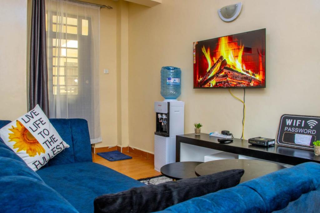 a living room with a blue couch and a fire on the wall at AirBnB in Nairobi