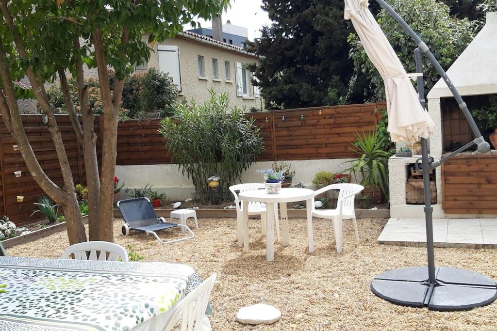eine Terrasse mit einem Tisch, Stühlen und einem Sonnenschirm in der Unterkunft Un logement dans pavillon Pèzenas in Pézenas