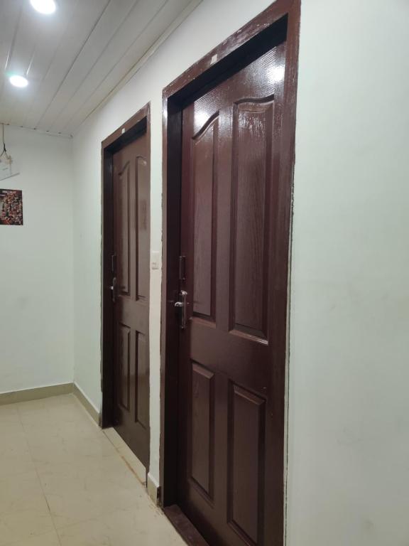 Cette chambre dispose de carrelage et de deux portes brunes. dans l'établissement Jungle valley Munnar, à Munnar