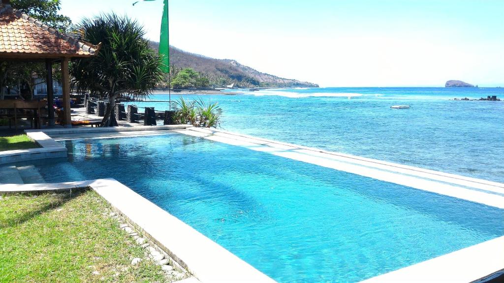 a large swimming pool next to the ocean at Amarta Beach Cottages in Candidasa