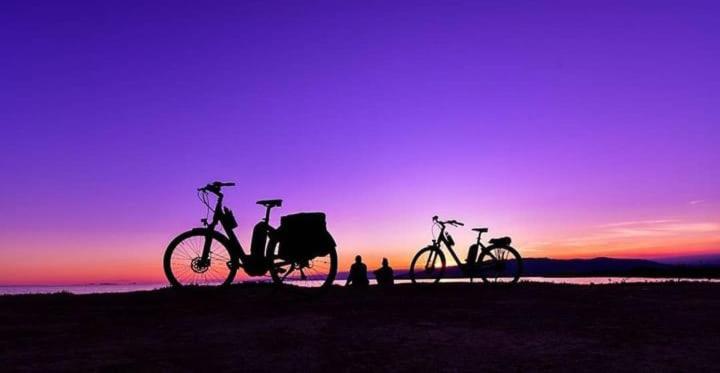 CAMPING DELTA NATURA LA TANCADA في أمبوستا: اثنين من الدراجات متوقفة على الشاطئ عند غروب الشمس