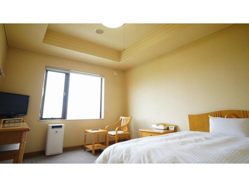 Schlafzimmer mit einem Bett, einem TV und einem Fenster in der Unterkunft Hotel Hounomai Otofuke - Vacation STAY 29517v in Otofuke