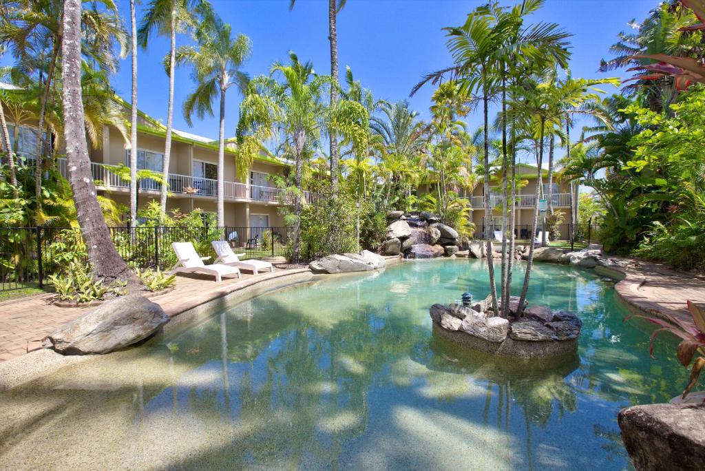 a swimming pool in a resort with palm trees at Hotel Tropiq in Cairns