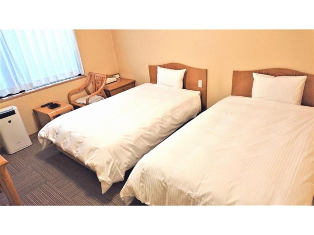 two beds in a hotel room with white sheets at Hotel Hounomai Otofuke - Vacation STAY 29507v in Otofuke