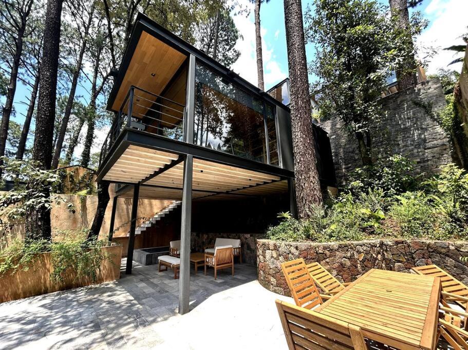 a glass house with a table and chairs at Cabaña Roble Boutique en Avándaro, Valle de Bravo in Valle de Bravo